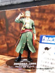 Rule 34 | 1boy, abs, boots, dual wielding, figure, green hair, haramaki, holding, jolly roger, male focus, muscular, one-eyed, one eye closed, one piece, photo (medium), pirate, robe, roronoa zoro, sash, scar, smile, solo, standing, sword, weapon