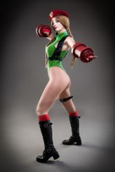 Rule 34 | 1girl, argentine (nationality), ass, bare legs, bare shoulders, blonde hair, boots, braid, cammy white, cammy white (cosplay), capcom, clenched hand, cosplay, curvy, fingernails, full body, gloves, green leotard, hat, highleg, highleg leotard, highres, huge ass, leotard, lips, long hair, looking at viewer, looking to the side, photo (medium), real life, shiny clothes, simple background, solo, sophie valentine, standing, street fighter, street fighter v, thong leotard, twin braids, very long hair, wide hips