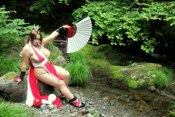 Rule 34 | breasts, brown eyes, brown hair, chouzuki maryou, cosplay, hand fan, hair ornament, hanging breasts, large breasts, leaning forward, long hair, photo (medium), plump, ponytail, shiranui mai, shiranui mai (cosplay), snk, the king of fighters, thick thighs, thighs, very long hair