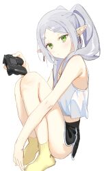 Rule 34 | 1girl, absurdres, alternate costume, bare shoulders, black shorts, blush, camisole, closed mouth, controller, elf, frieren, game controller, green eyes, highres, holding, long hair, pointy ears, ponytail, short shorts, shorts, simple background, sitting, socks, solo, sousou no frieren, syhan, twintails, white background, white camisole, yellow socks