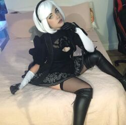 Rule 34 | 1girl, bed, black hairband, boots, breasts, cleavage, cosplay, cuban (nationality), female focus, green eyes, hairband, high heel boots, high heels, indoors, large breasts, looking at viewer, nier:automata, nier (series), photo (medium), short hair, sitting, skirt, solo, staryuuki, white hair, 2b (nier:automata), 2b (nier:automata) (cosplay)