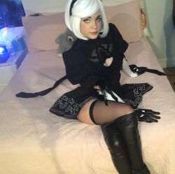 Rule 34 | 1girl, bed, black hairband, boots, breasts, cleavage, cosplay, cuban (nationality), female focus, green eyes, hairband, high heel boots, high heels, indoors, large breasts, looking at viewer, nier:automata, nier (series), photo (medium), short hair, skirt, solo, staryuuki, white hair, 2b (nier:automata), 2b (nier:automata) (cosplay)