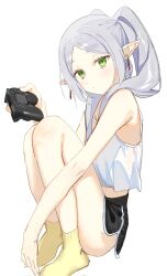 Rule 34 | 1girl, alternate costume, bare shoulders, black shorts, blush, camisole, closed mouth, controller, corrupted twitter file, frieren, game controller, green eyes, highres, holding, long hair, pointy ears, ponytail, short shorts, shorts, simple background, sitting, socks, solo, sousou no frieren, syhan, twintails, white background, white camisole, yellow socks