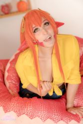 Rule 34 | 1girl, absurdres, artist name, blurry, blurry background, breasts, cleavage, cosplay, female focus, highres, indoors, lamia, lifted by self, long hair, lovelyspacekitten, miia (monster musume), monster girl, monster musume no iru nichijou, nose piercing, open mouth, orange hair, photo (medium), piercing, pointy ears, sharp teeth, snake tail, solo, tail, tattoo, teeth, tongue, tongue out, yellow eyes