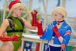 Rule 34 | 2girls, akemy sama, alternate costume, bare shoulders, blonde hair, braid, brazilian (nationality), cammy white, cammy white (cosplay), clenched hands, cosplay, fighting stance, hat, highleg, highleg leotard, highres, leotard, long hair, looking at another, multiple girls, nerokosplayer, photo (medium), real life, sleeveless, smile, standing, street fighter, street fighter 6, thong leotard, twin braids