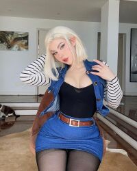 Rule 34 | 1girl, android 18, android 18 (cosplay), blonde hair, brazil, brazilian (nationality), breasts, cat, cleavage, cosplay, denim, denim skirt, dragon ball, dragon ball super, dragonball z, facing viewer, fegalvao, grey eyes, highres, indoors, looking at viewer, medium breasts, medium hair, photo (medium), real life, short hair, sitting, skirt, solo