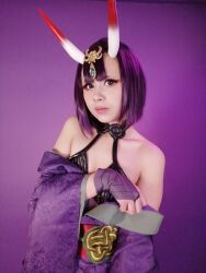 Rule 34 | 1girl, bare shoulders, cosplay, covering privates, fate/grand order, fate (series), female focus, highres, horns, looking at viewer, mexican (nationality), photo (medium), purple background, purple eyes, purple hair, rabbit.exe, real life, short hair, shuten douji (fate), shuten douji (fate) (cosplay), simple background, skin-covered horns, solo