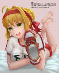 Rule 34 | 1girl, absurdres, ahoge, barefoot, blonde hair, fate/grand order, fate (series), feet, green eyes, gym uniform, hairband, highres, holding, holding shoes, long hair, looking at viewer, lying, nero claudius (fate), nero claudius (fate) (all), nero claudius (fate/extra), on stomach, open mouth, shoes, unworn shoes, single shoe, soles, solo (twsolo), toes, translated