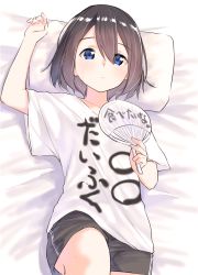 Rule 34 | 1girl, arm up, bed sheet, black shorts, blonde hair, blue eyes, brown hair, closed mouth, clothes writing, collarbone, commentary request, hair between eyes, hand fan, highres, holding, holding fan, looking at viewer, lying, on back, original, paper fan, pillow, shirt, short shorts, short sleeves, shorts, solo, suzunari shizuku, t-shirt, translation request, uchiwa, white shirt, yuki arare