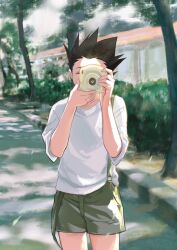 Rule 34 | 1boy, black hair, camera, cowboy shot, day, gon freecss, green overalls, highres, holding, holding camera, hunter x hunter, k.g (matsumoto zo), male focus, one eye closed, outdoors, overall shorts, overalls, shirt, short hair, solo, spiked hair, standing, taking picture, tree, white shirt