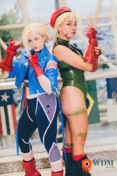 Rule 34 | 2girls, akemy sama, alternate costume, ass, bare shoulders, blonde hair, braid, brazilian (nationality), cammy white, cammy white (cosplay), clenched hands, cosplay, hat, highleg, highleg leotard, huge ass, leotard, long hair, looking at viewer, multiple girls, nerokosplayer, photo (medium), real life, sleeveless, smile, standing, street fighter, street fighter 6, thong leotard, twin braids