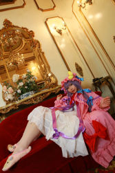 Rule 34 | 1girl, asian, bow, carpet, chandelier, cosplay, couch, crescent, dress, female focus, hat, highres, long hair, mob cap, patchouli knowledge, photo (medium), purple hair, red upholstery, ribbon, slippers, solo, table, tenshi myu, touhou, white dress
