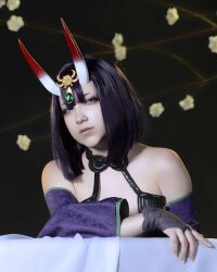 Rule 34 | 1girl, bare shoulders, blurry, blurry background, breasts, cosplay, fate/grand order, fate (series), female focus, highres, hiroto nyaa, horns, looking at viewer, mexican (nationality), photo (medium), purple eyes, purple hair, revealing clothes, short hair, shuten douji (fate), shuten douji (fate) (cosplay), skin-covered horns, small breasts, solo, upper body