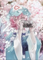 Rule 34 | 1girl, :d, blue hat, blurry, blurry background, camera, cherry blossoms, covered mouth, depth of field, hat, highres, holding, holding camera, japanese clothes, long sleeves, mob cap, newbokk, open mouth, outdoors, petals, pink eyes, pink hair, saigyouji yuyuko, short hair, smile, solo, touhou, tree, triangular headpiece, wide sleeves