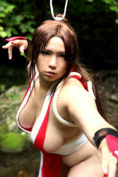 Rule 34 | breasts, brown eyes, brown hair, chouzuki maryou, cosplay, hair ornament, hand fan, hanging breasts, large breasts, leaning forward, long hair, photo (medium), plump, ponytail, shiranui mai, shiranui mai (cosplay), snk, the king of fighters, thick thighs, thighs, very long hair