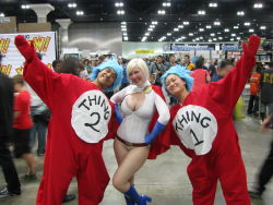 Rule 34 | 1girl, 2boys, belt, blonde hair, breasts, cape, cleavage, cleavage cutout, clothing cutout, cosplay, dc comics, gloves, highres, leotard, multiple boys, photo (medium), power girl, power girl (cosplay), superman (series), the cat in the hat, thing 1, thing 2