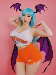 Rule 34 | 1girl, bare shoulders, bat wings, black trim, blue hair, blush (makeup), breasts, brown trim, capcom, cleavage, cosplay, cosplay photo, eyelashes, eyeliner, eyeshadow, fake wings, female focus, grey eyes, hands on own shoulders, head wings, highres, hooters, large breasts, lips, lipstick, long hair, makeup, morrigan aensland, morrigan aensland (cosplay), open mouth, orange shorts, orange trim, photo (medium), pink background, pink eyeshadow, pink lips, png conversion, real life, shirt, short shorts, shorts, sideboob, sleeveless, sleeveless shirt, solo, source request, tagme, teeth, thejulietttemichele, thick thighs, thighs, vampire (game), very long hair, white shirt, white trim, wide hips, wig, wings