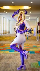 Rule 34 | 1girl, ass, blonde hair, blurry, blurry background, boku no hero academia, cosplay, female focus, horns, long hair, looking at viewer, mexican (nationality), mount lady, mount lady (cosplay), photo (medium), pink spirit (cosplayer), red eyes, smile, solo, standing, standing on one leg, teeth