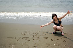 Rule 34 | 1girl, asian, beach, bikini, black bikini, black footwear, black hair, breasts, camera, japanese (nationality), japanese text, looking at viewer, namada, outdoors, partially translated, photo (medium), sandals, short hair, small breasts, smile, solo, squatting, swimsuit, tagme, text focus, translation request