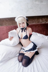 Rule 34 | 1girl, artist name, artoria pendragon (alter swimsuit rider) (fate), artoria pendragon (alter swimsuit rider) (fate) (cosplay), artoria pendragon (alter swimsuit rider) (second ascension) (fate), artoria pendragon (fate), bare shoulders, bed, bed frame, bed sheet, bikini, bikini top only, black bikini, black ribbon, black skirt, blonde hair, breasts, brown eyes, cleavage, closed mouth, cosplay, cosplay photo, ely (eeelyeee), fate/grand order, fate (series), frilled bikini, frilled bikini top, frilled skirt, frills, full body, hair ribbon, hugging object, indoors, kneeling, lips, long sleeves, maid headdress, medium breasts, miniskirt, navel, neck ribbon, off shoulder, on bed, photo (medium), pillow, pillow hug, ribbon, short hair, sidelocks, skirt, smile, solo, stomach, swimsuit, thighhighs, watermark, web address, zettai ryouiki