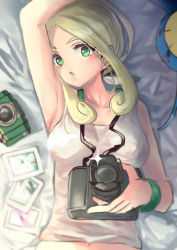 Rule 34 | 1girl, armpits, bare shoulders, bed sheet, blonde hair, blush, breasts, camera, collarbone, commentary request, creatures (company), e-co, eyelashes, from above, game freak, gen 3 pokemon, glint, green eyes, green wristband, holding, holding camera, looking at viewer, lying, medium breasts, navel, nintendo, on back, open mouth, photo (object), pokemon, pokemon (creature), pokemon xy, surskit, tank top, upper body, viola (pokemon), white tank top
