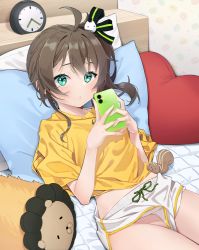 Rule 34 | 1girl, :o, agnamore, ahoge, bed, brown hair, cat hair ornament, cellphone, clock, commentary request, ebi frion (natsuiro matsuri), green eyes, hair ornament, heart, heart-shaped pillow, holding, holding phone, hololive, looking at viewer, lying, natsuiro matsuri, no panties, on back, parted lips, phone, pillow, shirt, short shorts, short sleeves, shorts, side ponytail, virtual youtuber, white shorts, yellow shirt