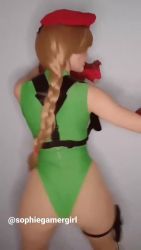 Rule 34 | 1girl, animated, argentine (nationality), bare legs, bare shoulders, blonde hair, braid, cammy white, cammy white (cosplay), capcom, cosplay, curvy, gloves, green leotard, hand on own hip, hat, highleg, highleg leotard, kicking, leotard, lips, long hair, looking at viewer, looking to the side, one eye closed, photo (medium), real life, shiny clothes, simple background, solo, sophie valentine, sound, standing, street fighter, street fighter v, thong leotard, twin braids, twitter username, very long hair, video, wide hips, wink