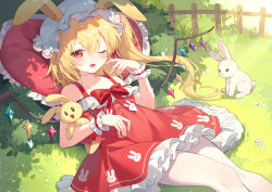 1girl absurdres animal_ears animal_print blonde_hair bow bush commentary crystal dress finger_to_face flandre_scarlet frilled_dress frilled_pillow frills hair_between_eyes hat heart heart-shaped_pillow highres holding holding_stuffed_toy layered_dress long_hair looking_at_viewer lying mob_cap on_back on_grass one_eye_closed open_mouth outdoors pantyhose pillow rabbit rabbit_ears rabbit_print red_bow red_dress red_eyes solo stuffed_animal stuffed_rabbit stuffed_toy suspenders touhou white_pantyhose wings yunweishukuang