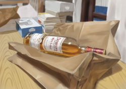 Rule 34 | absurdres, alcohol, bag, blurry, blurry background, book, book stack, bottle, commentary request, dewars scotch, highres, indoors, no humans, original, paper bag, scenery, still life, tissue box, yorishiem