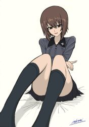 1girl absurdres artist_name black_collar black_skirt black_socks breasts brown_eyes brown_hair collar cross crossed_arms girls_und_panzer grey_shirt highres kuromorimine_school_uniform looking_at_viewer medium_breasts nishizumi_maho on_bed open_mouth pointing pointing_to_the_side school_uniform sekirei_tessar shirt short_hair simple_background sitting skirt smile socks solo