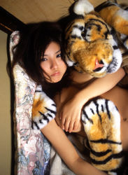 Rule 34 | 1girl, asian, black hair, blanket, brown hair, hanai miri, highres, indoors, long hair, looking at viewer, ns eyes 337, photo (medium), solo, stuffed animal, stuffed toy, tiger