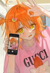 Rule 34 | 1girl, ahoge, blush, can lights, cellphone, cellphone photo, collarbone, dutch angle, frost fog, furrowed brow, hair between eyes, hair intakes, hair ornament, hairclip, hand up, heart, heart hair, highres, holding, holding phone, indoors, long hair, long sleeves, looking at viewer, ok sign, one side up, open mouth, orange eyes, orange hair, original, phone, pink shirt, print shirt, product placement, ringed eyes, selfie, shirt, smartphone, solo, tearing up, upper body, yellow eyes