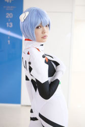 Rule 34 | 1girl, asian, ayanami rei, blue hair, breasts, color contacts, cosplay, cowboy shot, hairpods, highres, indoors, looking at viewer, looking back, namada, neon genesis evangelion, parted lips, photo (medium), plugsuit, red eyes, short hair, small breasts, solo, standing