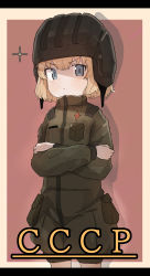 Rule 34 | 1girl, black headwear, blonde hair, blue eyes, closed mouth, commentary, cowboy shot, crossed arms, frown, girls und panzer, glaring, green jumpsuit, helmet, highres, insignia, jumpsuit, katyusha (girls und panzer), letterboxed, long sleeves, looking at viewer, pravda military uniform, russian text, s10021, shadow, short hair, short jumpsuit, solo, sparkle, tank helmet